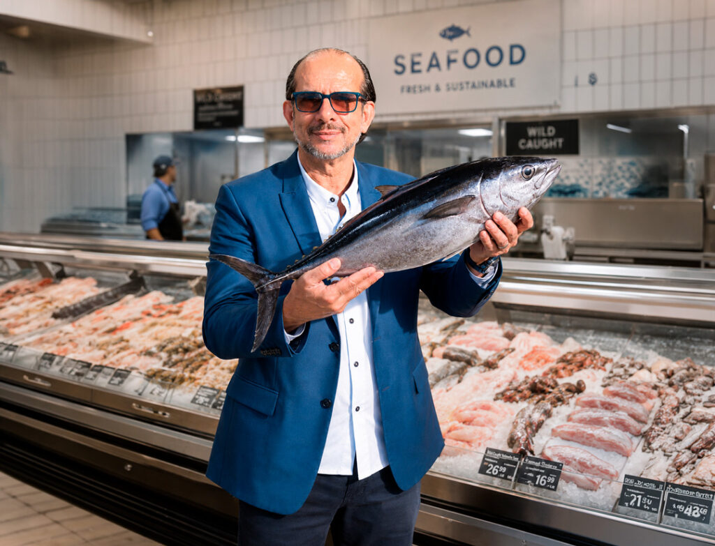Businessman holding a fresh tuna inside an American supermarket seafood section, representing Brazilian seafood opportunities for U.S. importers, retailers, and distributors.